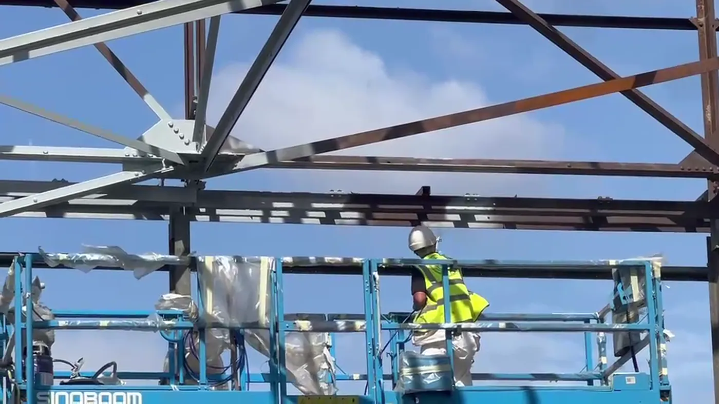 Premier Blasting operative applying coating to structural steel.