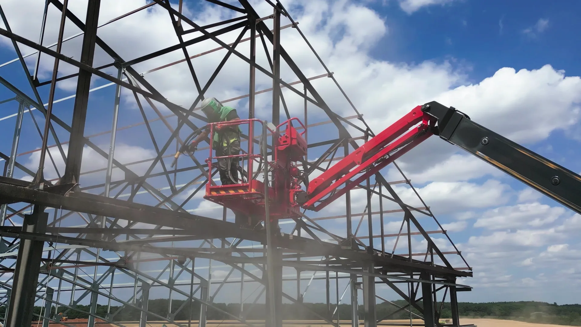 Wide view of structural steelwork, access equipment and an active Premier Blasting project site.