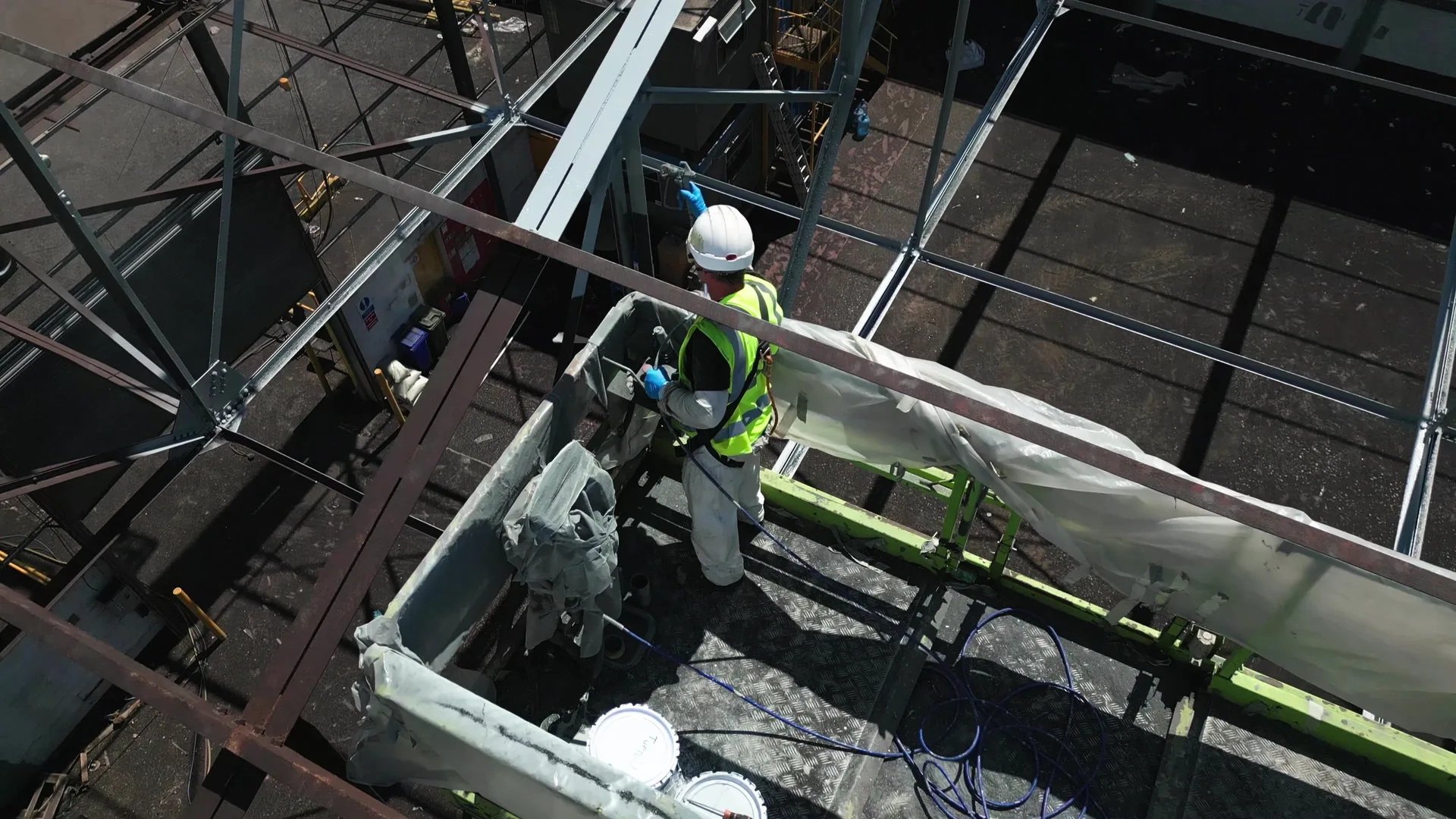 Elevated work platform beside structural steel during an on-site coating application sequence.