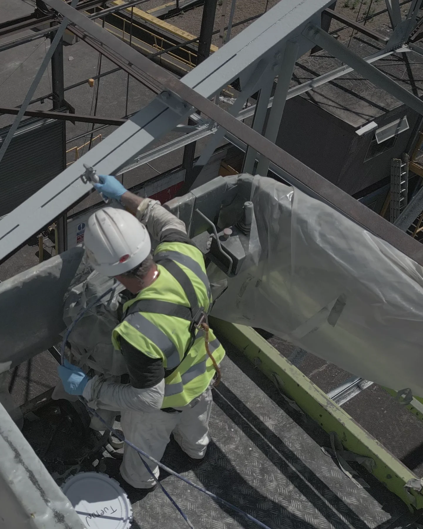 Portrait close view of an operative working from a powered access platform beside structural steel.